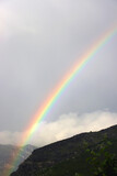 Beautiful rainbow over the mountain and gray sky. 