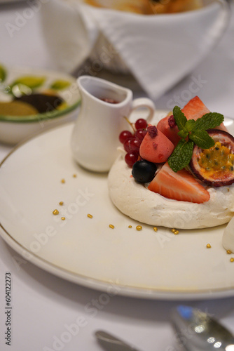A fine dining dessert in a fancy restaurant. White breakfast with fruits and syrup.  