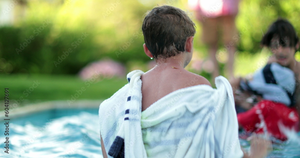 Family at the swimming pool on a hot summer day. Toddler child inside water with towel Family at the swimming pool on a hot summer day. Toddler child inside water with towel