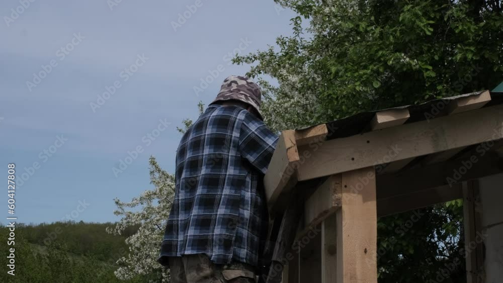 Resilient Construction: Elderly Craftsman Building his Own Home, One Screw at a Time. Retiree's Architectural Journey: Metal Shingle Installation by a Skilled Senior Builder