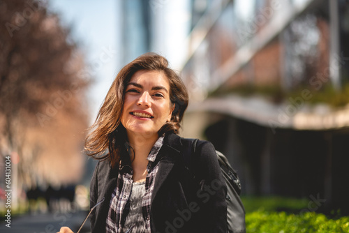 Modern, beautiful and young executive: sophisticated woman with sunglasses and backpack in urban park in business district