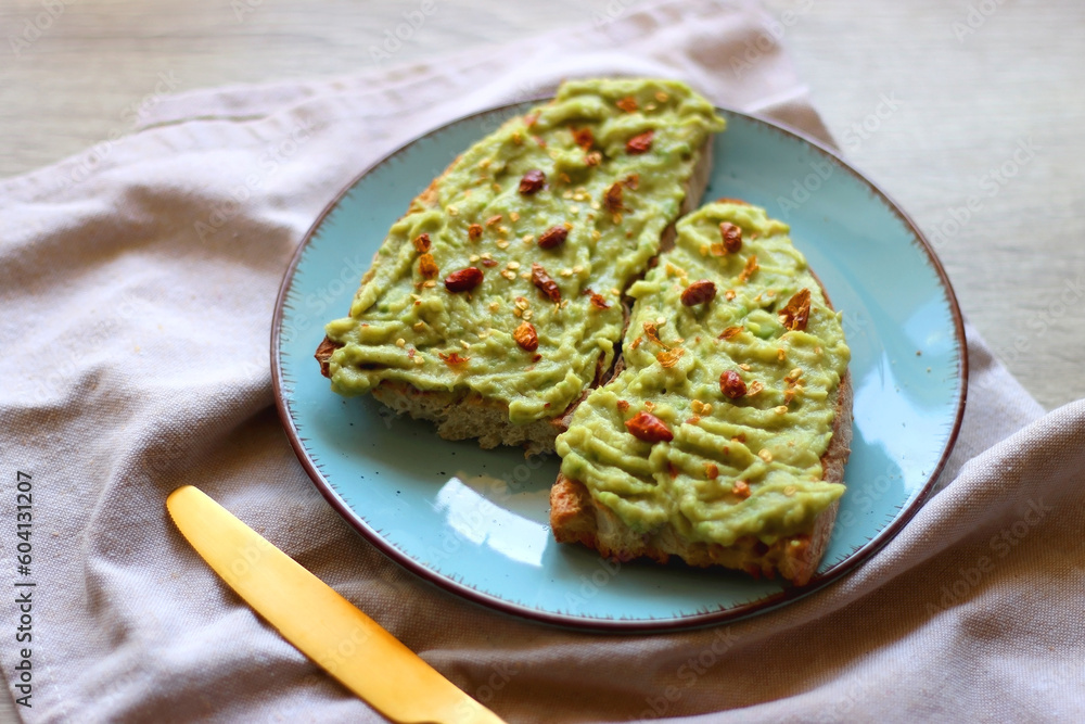Turquoise plate with two pieces of avocado toast on wooden table. Selective focus. Turquoise plate with two pieces of avocado toast on wooden table. Selective focus.