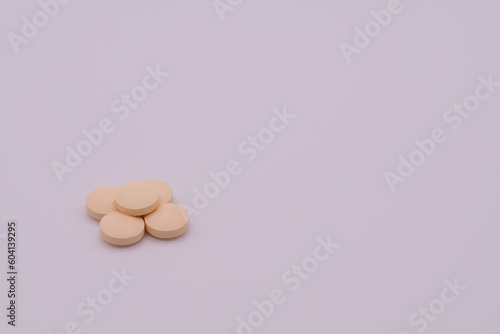 Stack of pale colored pills on a white background
