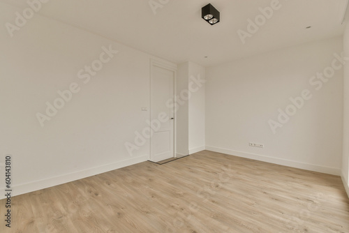 an empty room with white walls and wood flooring on the right side, there is a door in the corner to the left