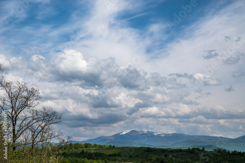 Landscape with blue mountains on the horizon and a big blue cloudy sky.