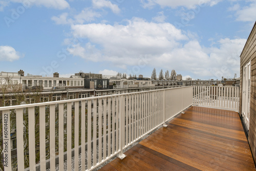 a balcony with wood flooring and white railings on the side of an apartment building looking out to the city
