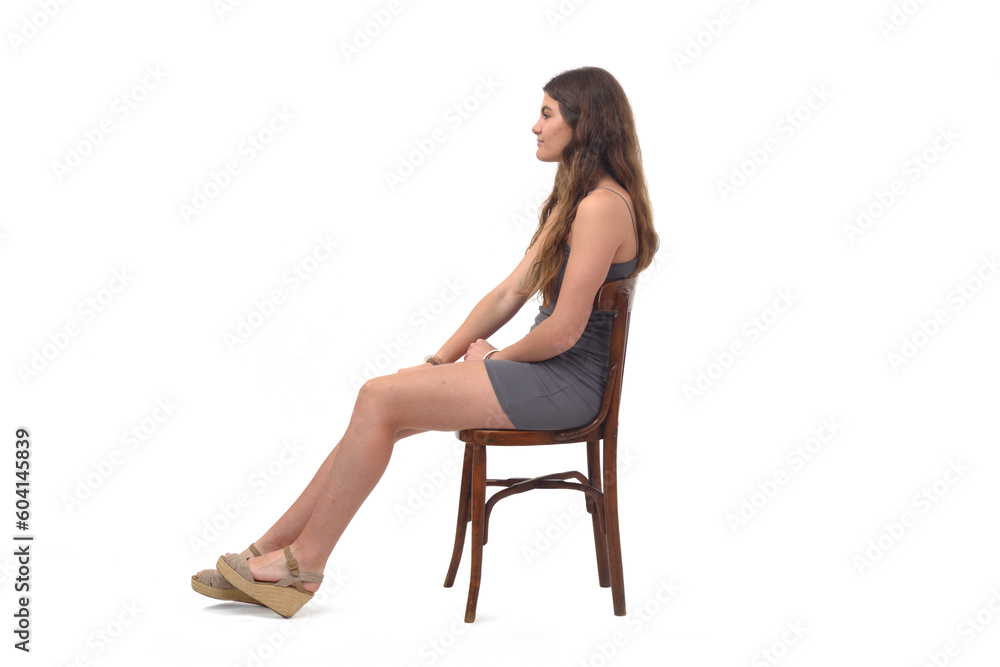 side view of young girl sitting on chair with stretched legs on white background side view of young girl sitting on chair with stretched legs on white background