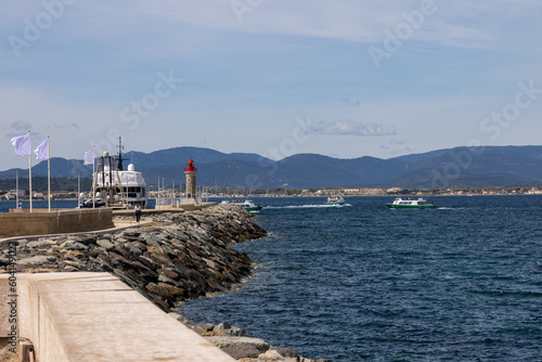 Port entrance with ships, yachts, lighthouse and quay wall as well as the Mediterranean Sea in Saint Tropez, Cote d'Azur, French Riviera © A.Freund
