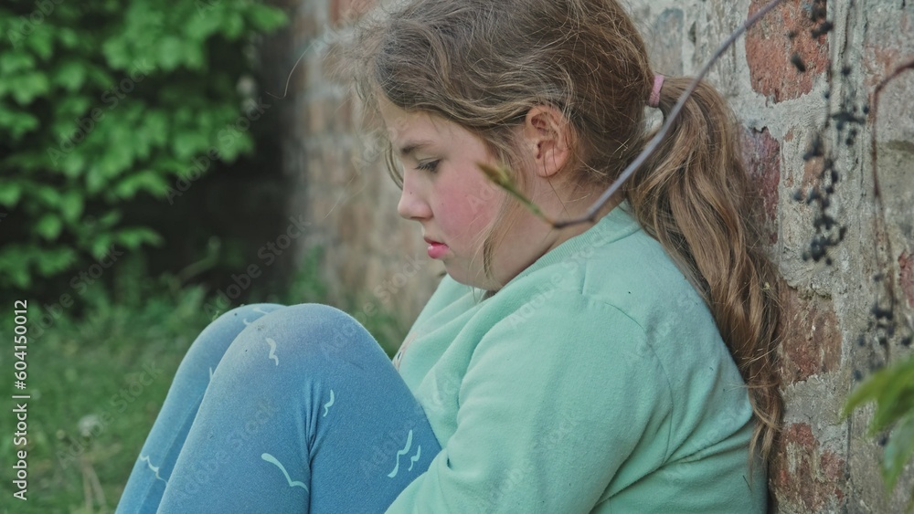 Upset Frustrated Depressed Young Caucasian Girl Sitting Alone Outdoors Against Brick Wall Hiding from People Parents and Friends
