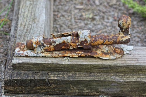 one white brown rusty old iron latch on a gray wooden frame outdoors