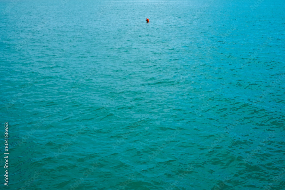 Small buoy floating in the middle of the sea near the pier