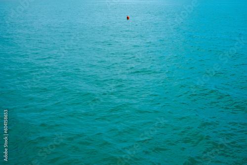Small buoy floating in the middle of the sea near the pier