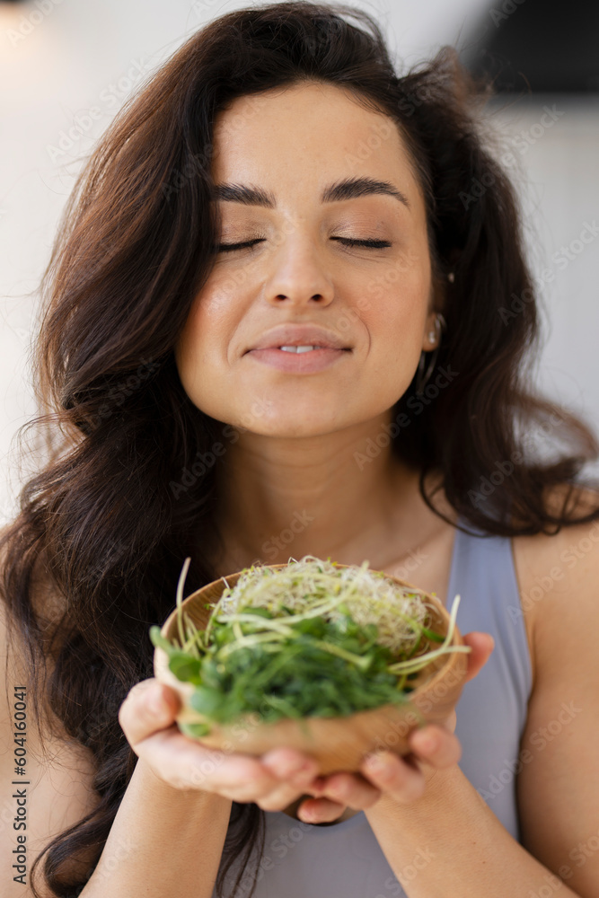 Vertical view of the beautiful smiling woman holding bowl with fresh micro green Vertical view of the beautiful smiling woman holding bowl with fresh micro green