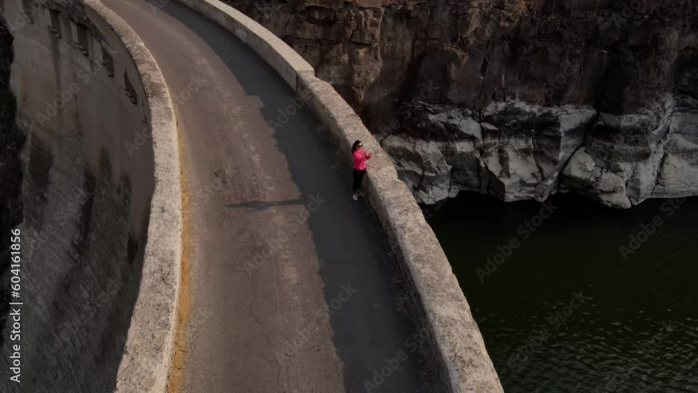 Aerial shot of an Asian woman hiking across the historic 100 year old Salmon Falls Dam in Southern Idaho Aerial shot of an Asian woman hiking across the historic 100 year old Salmon Falls Dam in Southern Idaho