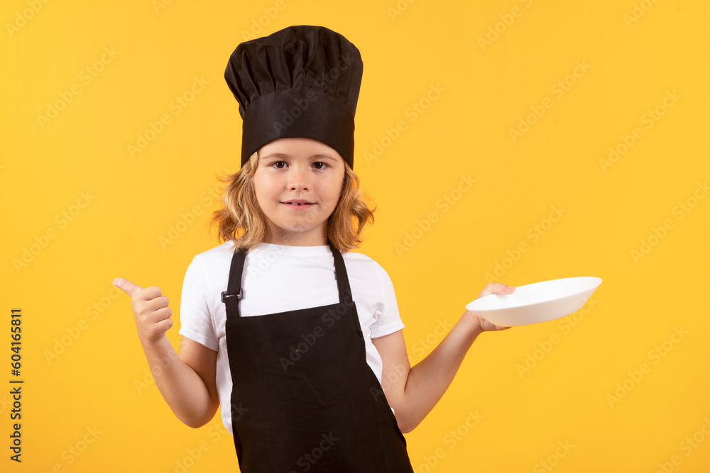 Funny child cook with cooking plate. Child cooking, little chef prepares food. Kid boy in chefs hat and apron on yellow studio isolated background. Funny child cook with cooking plate. Child cooking, little chef prepares food. Kid boy in chefs hat and apron on yellow studio isolated background.