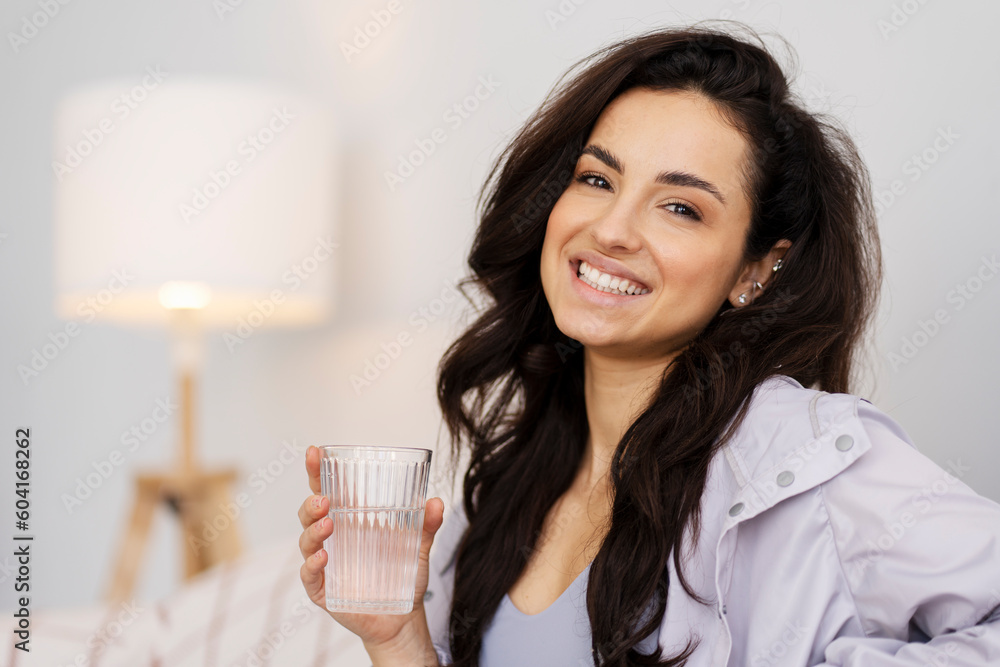 Portrait of cheerful sporty latin woman holding glass of fresh water Portrait of cheerful sporty latin woman holding glass of fresh water