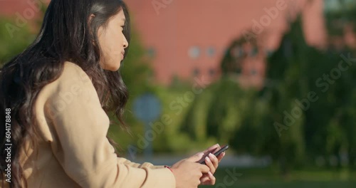 Young teenage latin college student using social networks with her smartphone in a park