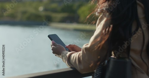 Young teenage latin college student using social networks with her smartphone in a park