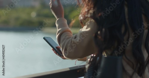 Young teenage latin college student using social networks with her smartphone in a park