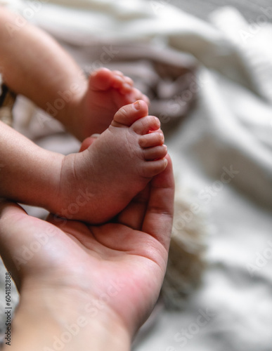 Newborn tiny foot in mothers hand close up 