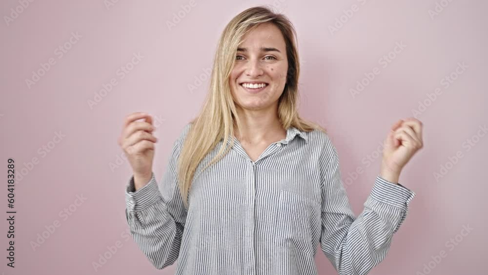 Young blonde woman smiling confident dancing over isolated pink background Young blonde woman smiling confident dancing over isolated pink background