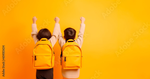 Rear view of two children with school bags with their arms raised on a yellow background with copy space. Generative AI