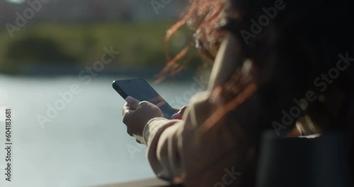 Young teenage latin college student using social networks with her smartphone in a park