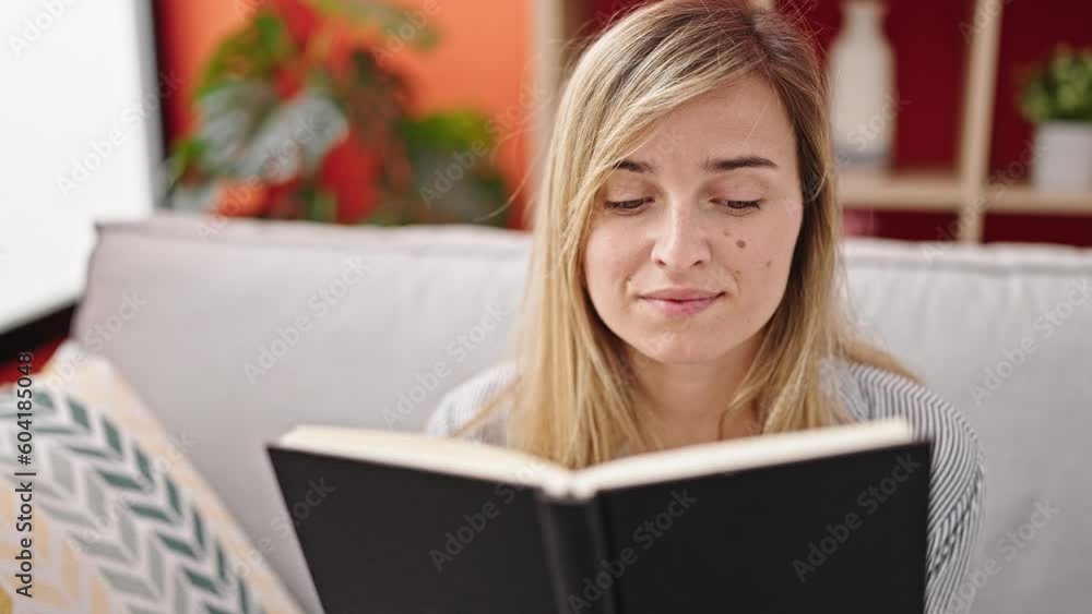 Young blonde woman reading book sitting on sofa at home Young blonde woman reading book sitting on sofa at home