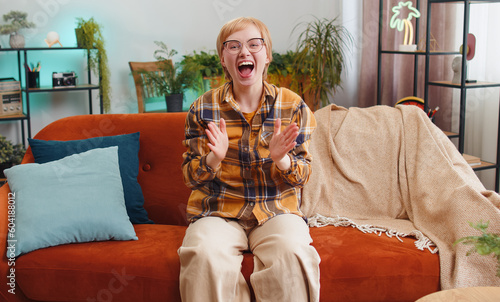 Wallpaper Mural Happy young woman shouting, celebrating success, winning, goal achievement good news raising fists in gesture I did it, lottery luck at modern home apartment. Girl in living room sitting on couch Torontodigital.ca