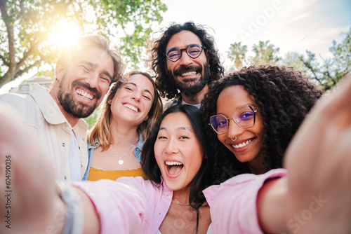 Group of multiracial young people smiling and taking a selfie together. Close up portrait of happy asian teenage woman laughing with his cheerful friends. Classmates having fun on friendly meeting photo