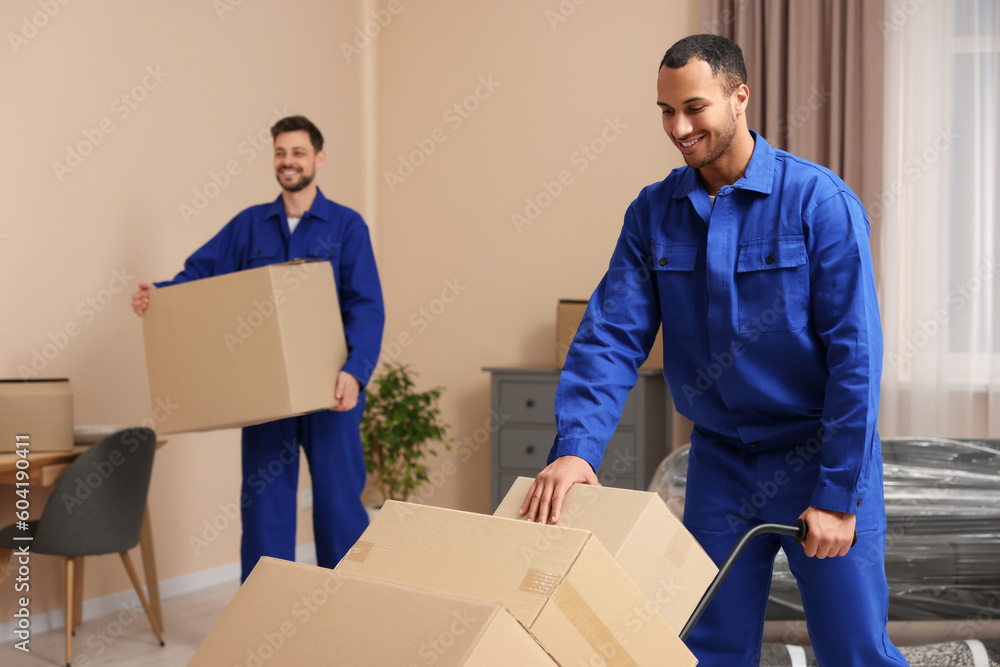 Male movers with cardboard boxes in new house Male movers with cardboard boxes in new house