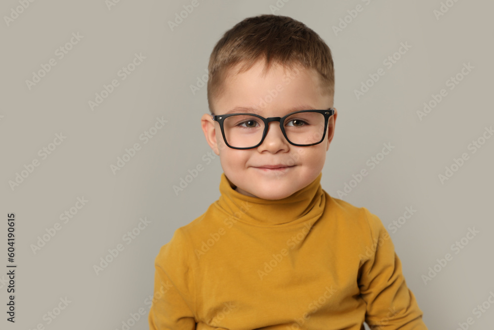 Cute little boy in glasses on light grey background. Space for text