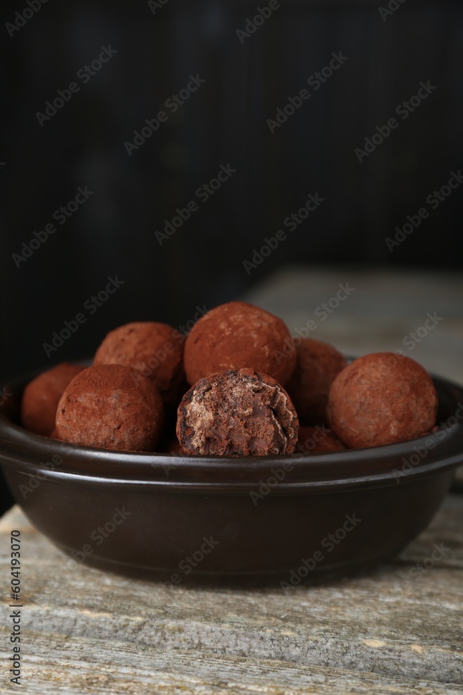 Delicious chocolate candies powdered with cocoa on wooden table Delicious chocolate candies powdered with cocoa on wooden table