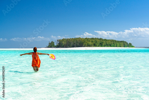 Cheerful woman with arms outstretched standing in the turquoise sea, Zanzibar, Tanzania photo