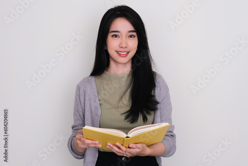 Young Asian women smiling confident at the camera while holding a book photo