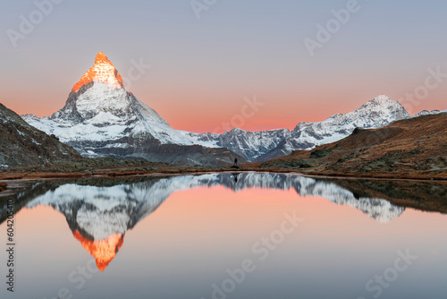 Hiker admiring the Matterhorn reflected in the Riffelsee lake at sunrise, Gornergrat, Zermatt, canton of Valais, Switzerland