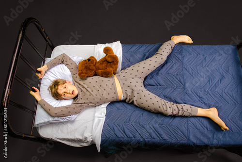 фотографія Frightened young boy lying in bed looking up at something scary in the air above