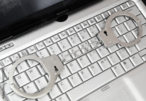 Online crimes and frauds concept. Laptop computer with handcuffs, top view.