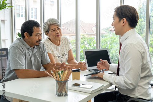 Asian young employee is offering about life insurance plan to aged couple
