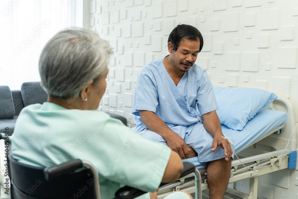 Female patient visit her male friend who sitting on patient bed in hospital Female patient visit her male friend who sitting on patient bed in hospital