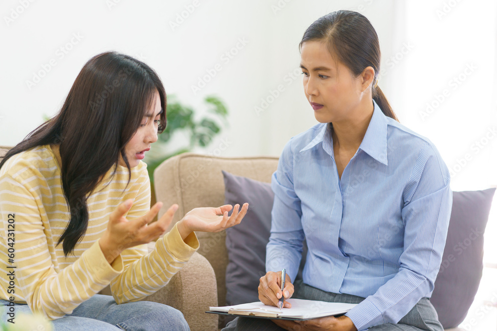 Female patients explaining her mental problem to psychologist while she writing notes in clipboard - obrazy, fototapety, plakaty 