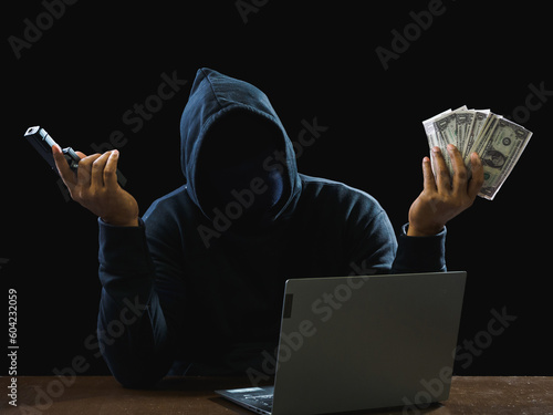 Tela Hacker spy man wearing a black shirt, sitting on a chair and a table, is a thief, hands holding money, counting the amount obtained from hijacking or robbing, in pitch-black room