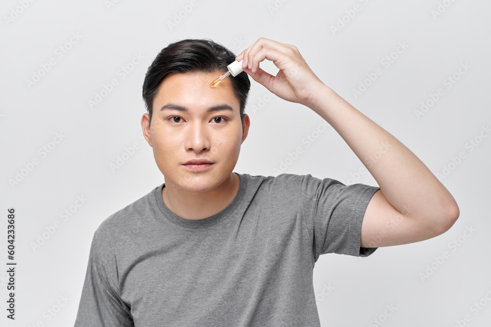 portrait of handsome guy applying serum beauty product on his face using glass pipette portrait of handsome guy applying serum beauty product on his face using glass pipette