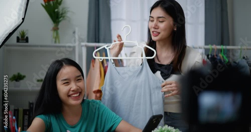 Footage slow motion shot of Young Beautiful Asian women live streaming to sale fashion clothes at home studio, They are talking in front of digital camera, influencer on social media concept