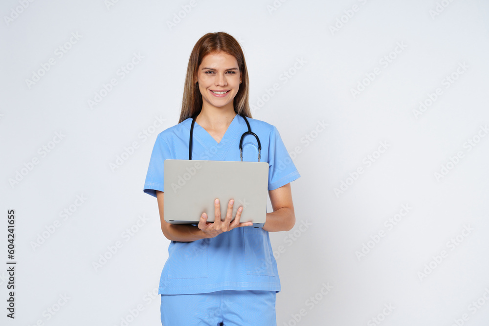 Portrait of smiling young woman doctor with stethoscope holding in hands laptop isolate on white background. Portrait of smiling young woman doctor with stethoscope holding in hands laptop isolate on white background.