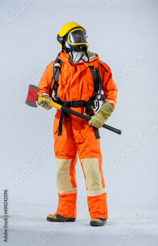 Vertical picture of firefighter holding iron axe while looking sideways with confidence on white background. © DSM