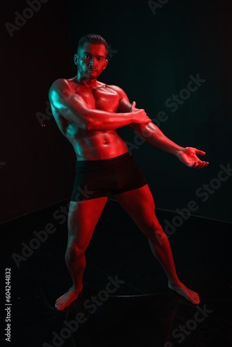 Man bodybuilder posing muscles with nude fitness torso, isolated on black background in neon light. Advertising, sports, active lifestyle, colored light, competition, challenge concept.  © SHOTPRIME STUDIO