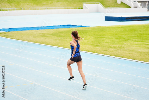 Woman, back and running on stadium track in fitness, exercise or workout for cardio training outdoors. Fit, active or sporty female person, runner or athlete sprinting competition, exercising or race