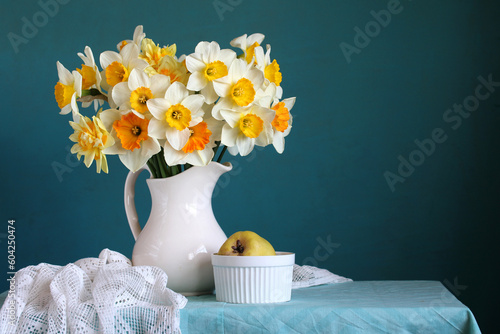 Tableau sur toile A bouquet of garden daffodils and quince on the table on a blue background