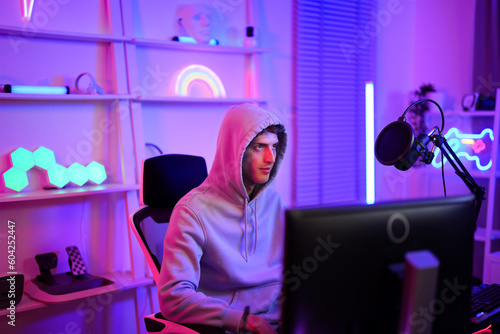 Caucasian teenager boy waiting team for playing tournament challenge online on computer technology in neon gaming room